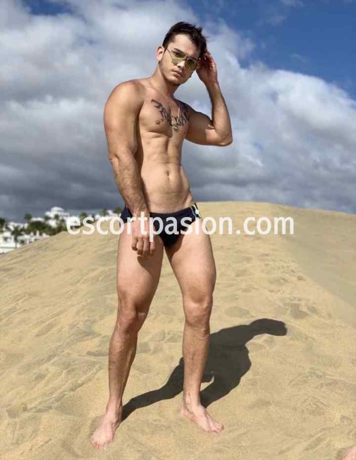 chico gay cachondo y vicioso en ropa de baño muy sexy tomando sol en la playa